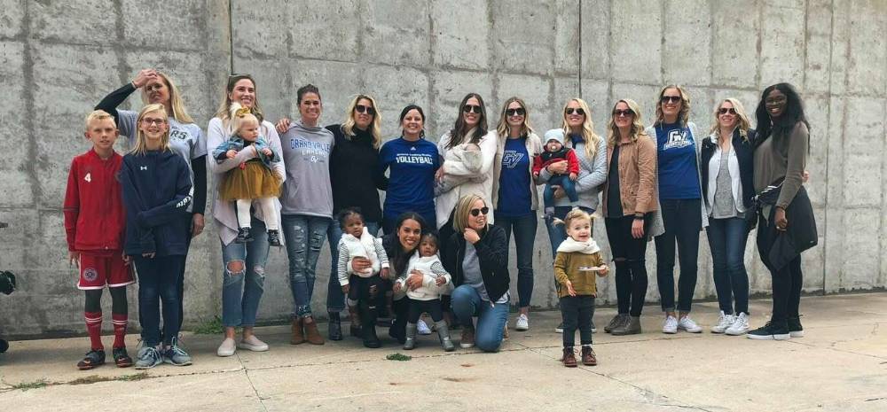 GVSU volleyball alumni and their kids pose for a photo outside